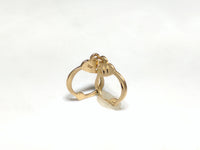 In the center: a pair of 14 karat gold handcuffs pendant standingan angle with the 14K stamp in view - Popular Jewelry