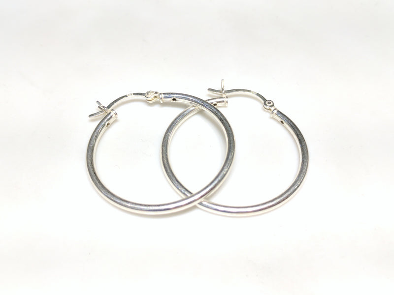 A pair of sterling silver hoop earrings in plain high polished finished stacked and laying flat Popular Jewelry