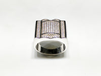 In the center: white sterling silver men's rings set with cubic zirconia in a micro pave setting standing up facing viewer made by Popular Jewelry in New York City