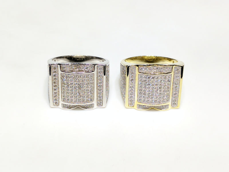 From left to right: white and yellow sterling silver men's rings set with cubic zirconia in a micro pave setting laying side by side facing viewer made by Popular Jewelry in New York City
