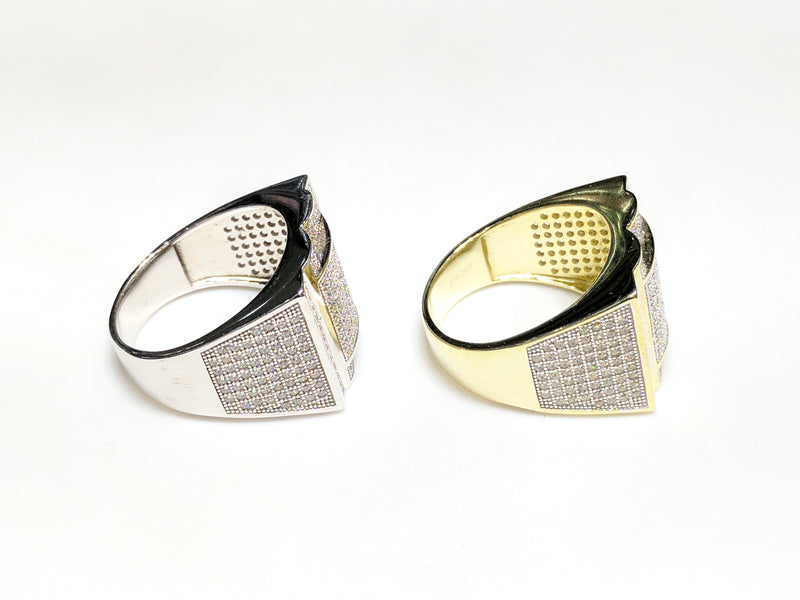 From left to right: white and yellow sterling silver men's rings set with cubic zirconia in a micro pave setting laying side by side in side view made by Popular Jewelry in New York City