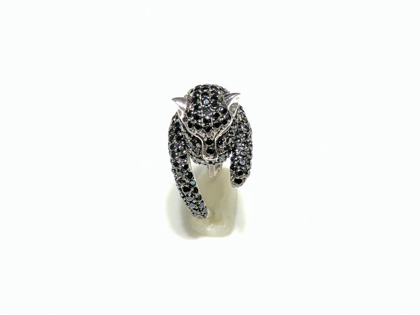In the center: a sterling silver panther shaped band iced out with black cubic zirconia  in a micro pave setting with its head facing front made by Popular Jewelry in New York City