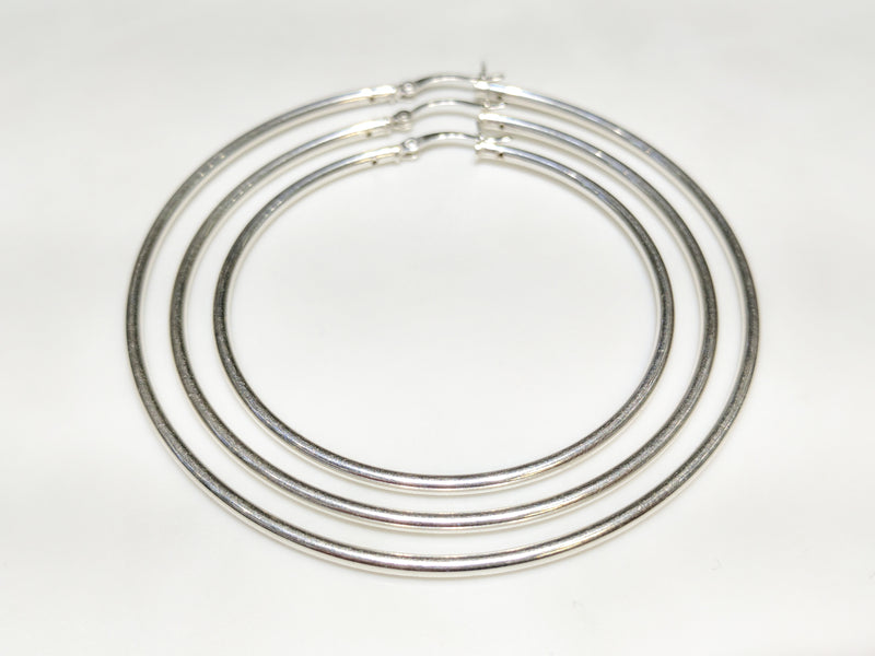 In the center: three sterling silver hoop earrings in plain high polished finish of different diameters arranged within one another from smallest to largest - Popular Jewelry
